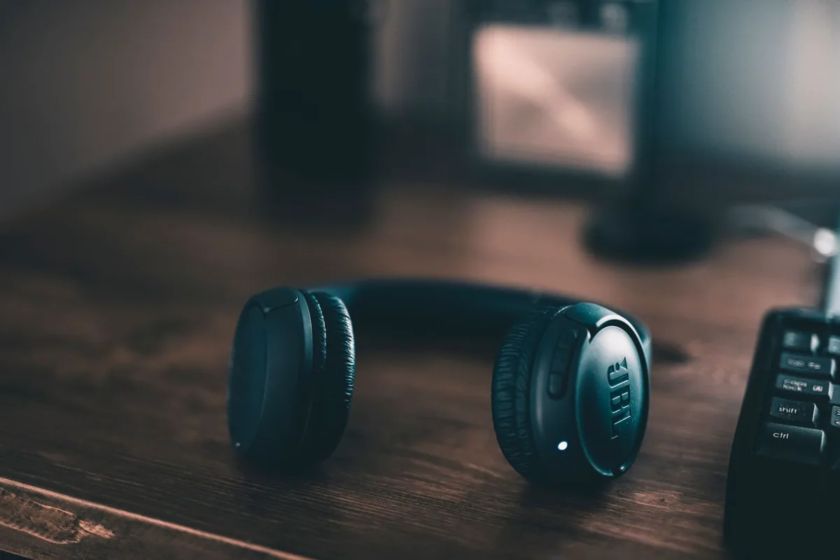 Headphone escuro apoiado em uma mesa de madeira.
