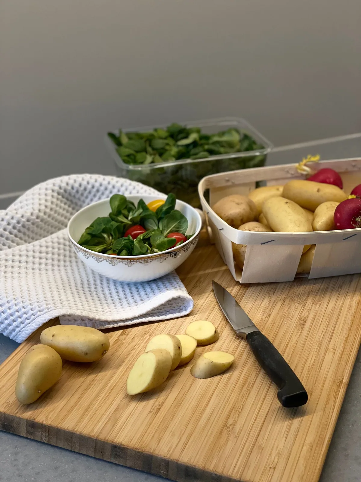 Batatas cortadas sobre uma tábua, com folhas verdes ao lado.