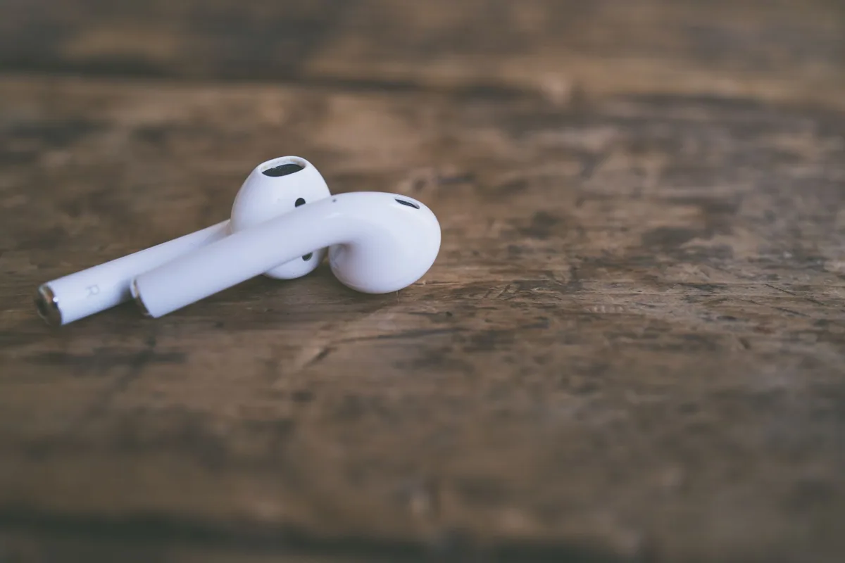 Fones de ouvido brancos sem fio sobre uma superfície de madeira.