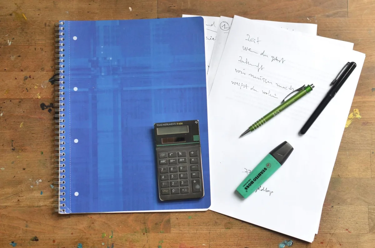Calculadora e caderno para comparar o custo de uma compra.